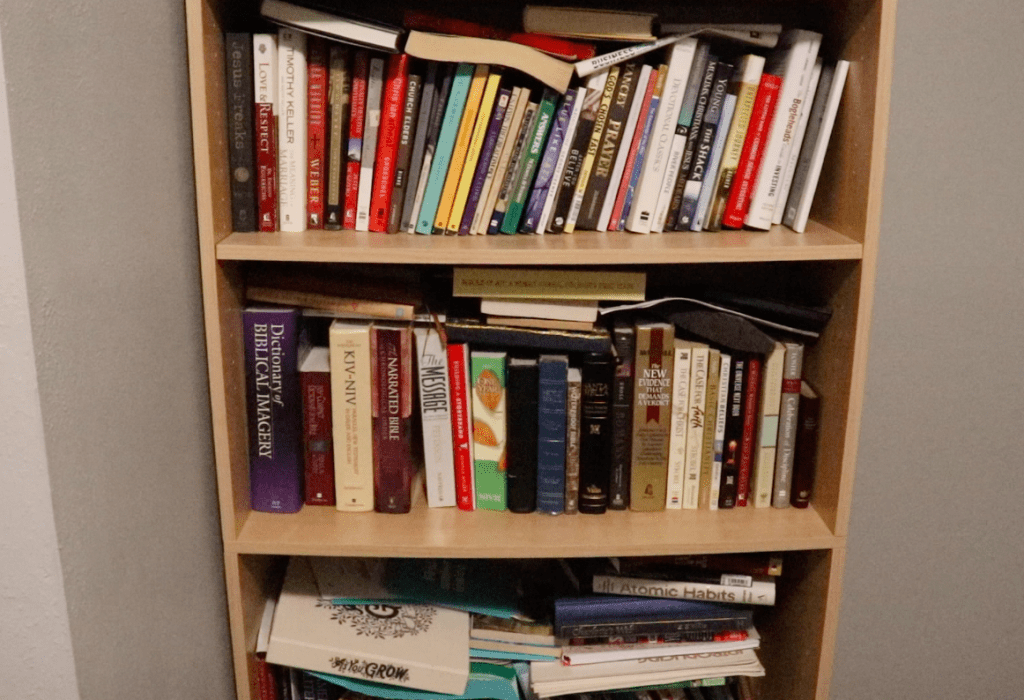 Bookcase against a grey wall packed with all sorts of different books